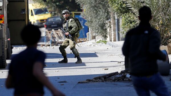 فلسطينيون يرشقون جنديًا إسرائيليًا بالحجارة أثناء غارة إسرائيلية على بيت جالا بالضفة الغربية التي تحتلها إسرائيل - سبوتنيك عربي