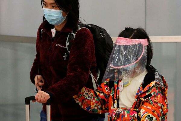 امرأة وطفلتها يرتديان أقنعة واقية لدى وصولهما إلى محطة القطارات في هونغ كونغ، 29 يناير 2020 - سبوتنيك عربي