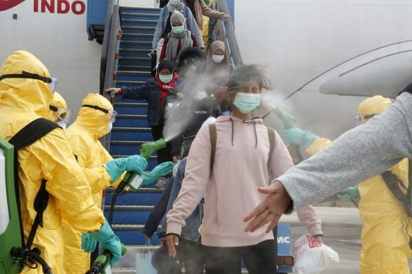 أطباء يقوم برش مطهر طبي على مواطنين إندونيسيين بعد وصولهم من مدينة ووهان الصينية، 2 فبراير 2020 - سبوتنيك عربي
