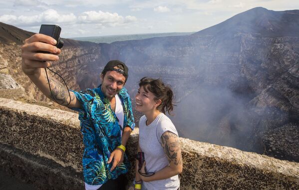 سياح يلتقطون صور سيلفي على خلفية بركان ماسايا، على بعد 30 كلم من مانغوا، نيكاراغوا - سبوتنيك عربي