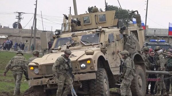 جنود تجمعوا بجانب قافلة عسكرية أمريكية عالقة في قرية خربة عمو شرق مدينة القامشلي في سوريا  - سبوتنيك عربي