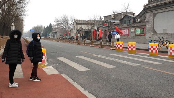 رجلان يرتديان أقنعة الوجه بينما يمشيان في شارع فارغ في بكين في الصين - سبوتنيك عربي
