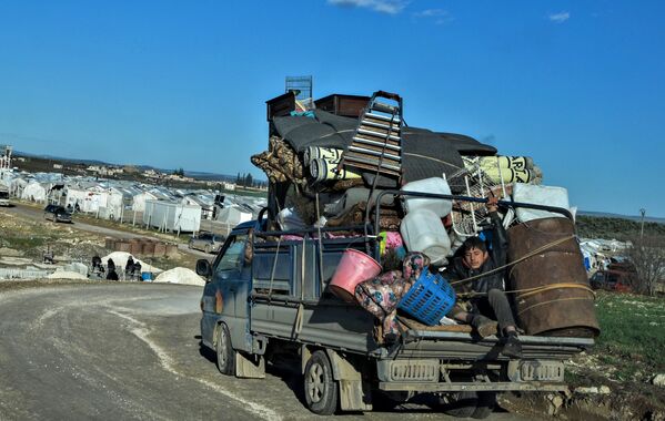 لاجئون سوريون يصلون إلى مخيم للنازحين بالقرب دير بلّوط‎، بالقرب من الحدود التركية، 9 فبراير 2020 - سبوتنيك عربي