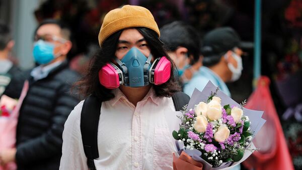 رجل يرتدي قناعا واقيا ويحمل باقة زهور بمناسبة يوم فالنتاين (عيد الحب) في هونغ كونغ، الصين 14 فبراير 2020 - سبوتنيك عربي