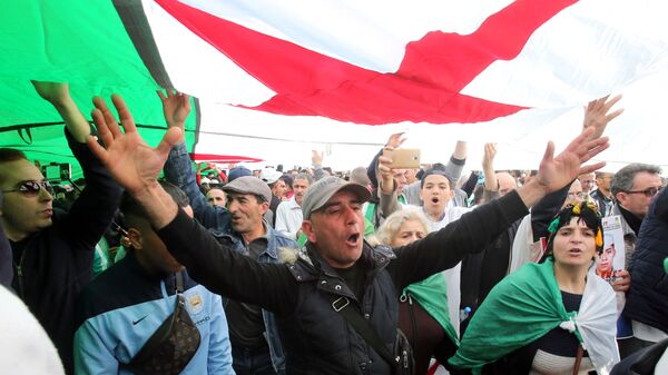 متظاهرون جزائريون يحملون العلم الوطني بعد مرور عام على بدء الاحتجاجات الأسبوعية التي تدعو إلى إصلاح شامل للنخبة الحاكمة ووضع حد للفساد وانسحاب الجيش من السياسة في الجزائر العاصمة  14 فبراير/ شباط 2020 - سبوتنيك عربي