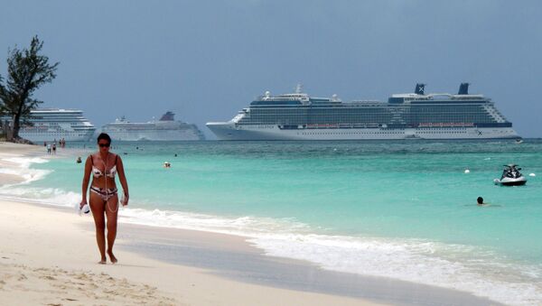 امرأة تمشي على شاطئ سيفن مايل مع ثلاث سفن سياحية تقف في ميناء بجورج تاون بجزر كايمان - سبوتنيك عربي