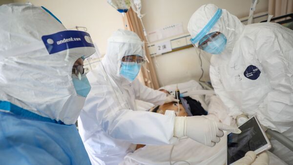 أطباء يرتدون سترات واقية يوقعون الكشف الطبي على مريض مصاب بفيروس كورونا داخل جناح منعزل بمستشفى ووهان الصيني - سبوتنيك عربي