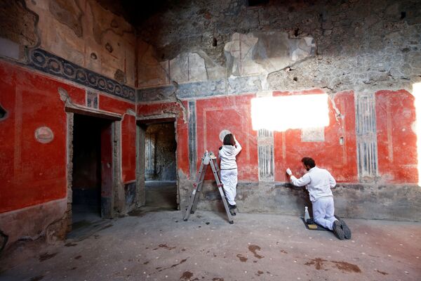 علماء آثار يعملون على لوحة جدارية في منزل العشاق (Casa degli Amanti) ، أحد ثلاثة منازل تم ترميمها (منازل قديمة)، أعيد فتحها أمام الجمهور في الموقع الأثري بومبي، إيطاليا 18 فبراير 2020 - سبوتنيك عربي
