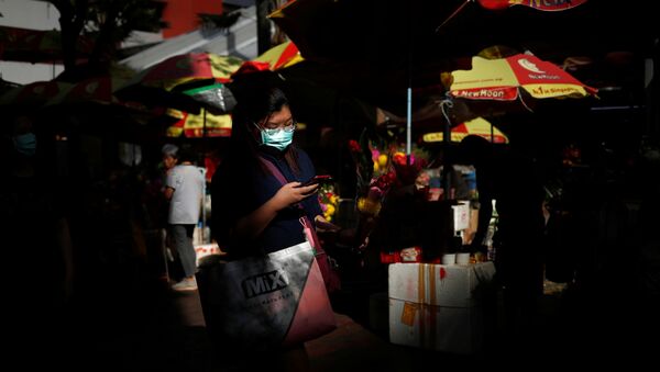 سيدة ترتدي كمامة واقية من فيروس كورونا المستجد وتحمل في يدها باقة زهور خارج معبد كوان إيم هود تشو في سنغافورة - سبوتنيك عربي