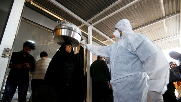 موظف طبي عراقي يفحص درجة حرارة راكبة وسط تفشي فيروس كورونا الجديد لدى وصولها إلى معبر شلامشة الحدودي بين العراق وإيران - سبوتنيك عربي
