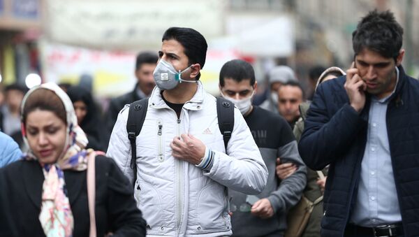 مواطنون إيرانيون يرتدون كمامات واقية من فيروس كورونا خلال سيرهم في أحد شوارع طهران - سبوتنيك عربي