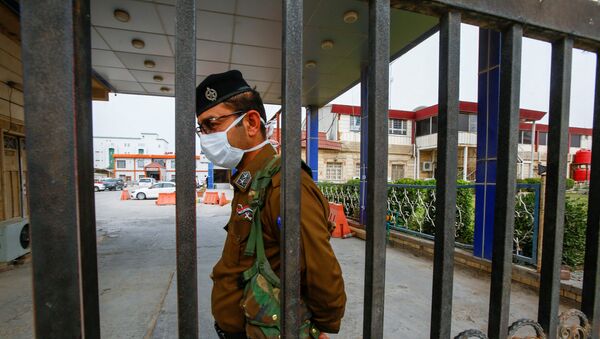 ضابط أمن عراقي يرتدي قناعًا وقائيًا في أحد المستشفيات في أعقاب تفشي فيروس كورونا الجديد في مدينة النجف المقدسة في العراق - سبوتنيك عربي