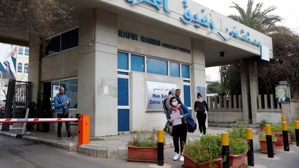 أشخاص يرتدون أقنعة الوجه يمشون خارج مستشفى رفيق الحريري حيث يتم وضع الحجر الصحي في لبنان  - سبوتنيك عربي