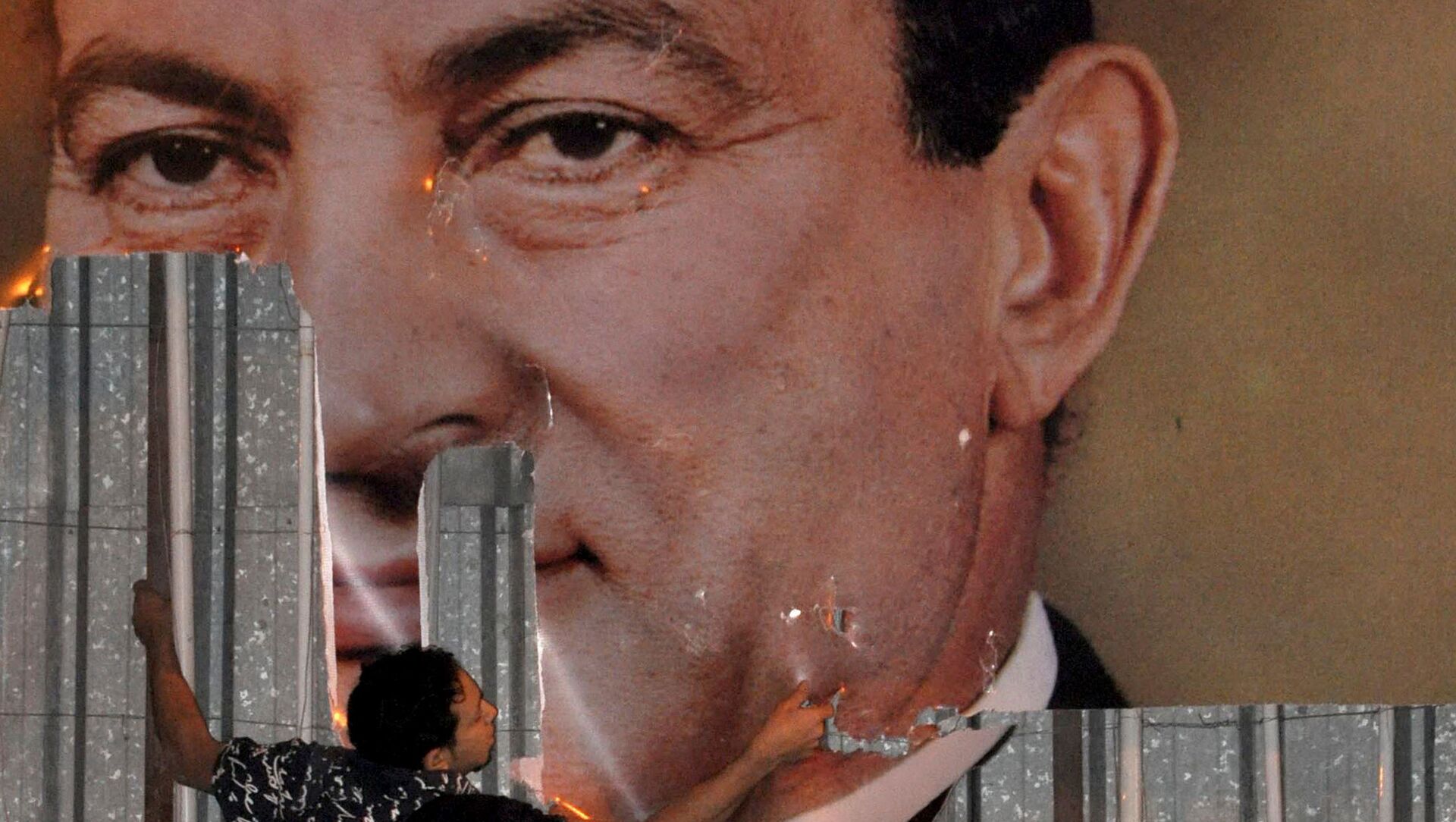 متظاهر مناهض للحكومة يشوه صورة الرئيس المصري حسني مبارك في الإسكندرية في 25 يناير 2011 - سبوتنيك عربي, 1920, 11.02.2021