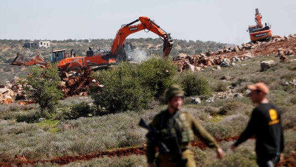جرافة تحرسها القوات الإسرائيلية تقوم بتجريف الأراضي بالقرب من قرية قصرة الفلسطينية في الضفة الغربية المحتلة - سبوتنيك عربي