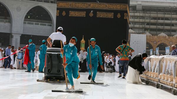 عمال النظافة يرتدون أقنعة واقية للوجه بعد تفشي فيروس كورونا ويمسحون الأرض عند الكعبة المشرفة في المسجد الحرام في مدينة مكة المكرمة - سبوتنيك عربي