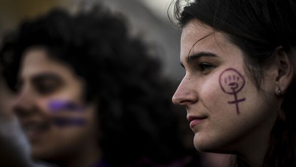امرأة مرسوم على وجهها رمز اليد النسوية خلال حضورها مظاهرة بمناسبة اليوم العالمي للمرأة في لشبونة، البرتغال، 8 مارس/ آذار 2019 - سبوتنيك عربي