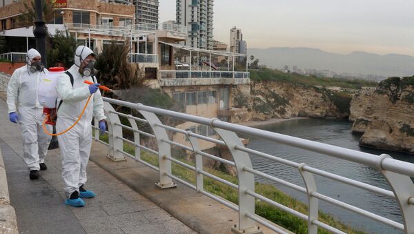 موظفون من شركة مطهرة يعقمون الدرابزين كإجراء احترازي ضد انتشار فيروس كورونا في كورنيش بيروت على شاطئ البحر - سبوتنيك عربي