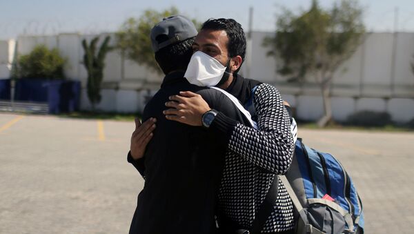 رجل فلسطيني يرتدي قناعًا وسط احتياطات فيروس كورونا لدى عودته من الخارج عند معبر رافح الحدودي مع مصر في جنوب قطاع غزة - سبوتنيك عربي