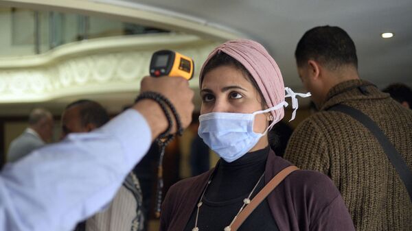 امرأة ترتدي كمامة طبية وتخضع لفحص درجة حرارة جسدها على متن قارب سياحي في مدينة الأقصر بجنوب مصر،  للكشف عن فيروس كورونا المستجد، 8 مارس/ آذار 2020 - سبوتنيك عربي