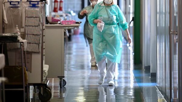 عمال طبيون يرتدون الأقنعة الواقية والبدلات يسيرون في وحدة العناية المركزة في مستشفى Oglio Po حيث يتم علاج المرضى الذين يعانون من مرض فيروس كورونا في إيطاليا - سبوتنيك عربي