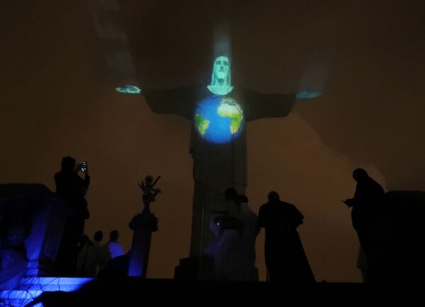 أضاء تمثال المسيح الفادي بألوان الكرة الأرضية المصابة بمرض فيروس كورونا (COVID-19) في ريو دي جانيرو، البرازيل، 18 مارس 2020. - سبوتنيك عربي