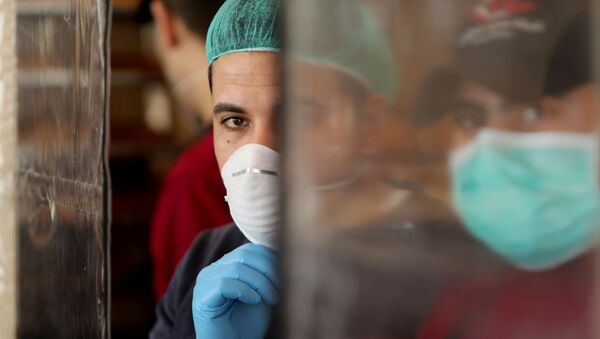 فلسطينيون يرتدون أقنعة كإجراء وقائي ضد مرض فيروس كورونا يعملون في مخبز في مدينة غزة - سبوتنيك عربي