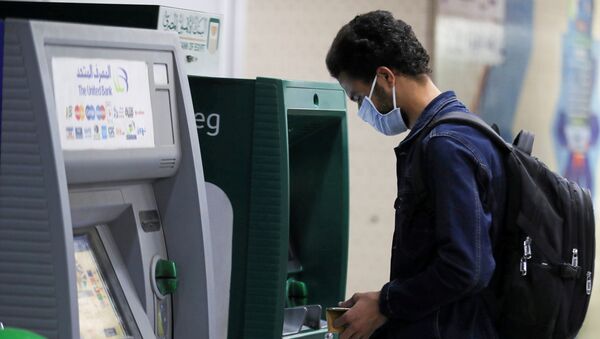 رجل يرتدي قناع الوجه الواقي يسحب الأموال من أجهزة الصراف الآلي في محطة مترو الشهداء بينما تكثف مصر جهودها لإبطاء انتشار فيروس كورونا - سبوتنيك عربي