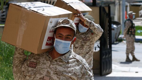 جنود يحملون طرودًا غذائية لتوزيعها على بعض سكان مدينة الزرقاء بعد تطبيق إغلاق صارم وسط مخاوف من انتشار مرض فيروس كورونا في الأردن - سبوتنيك عربي