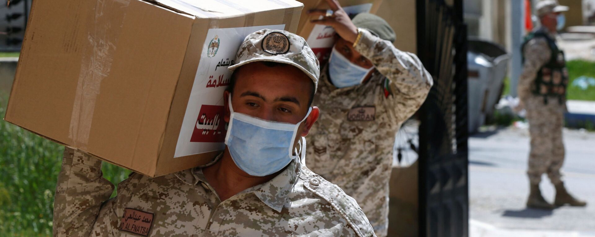 جنود يحملون طرودًا غذائية لتوزيعها على بعض سكان مدينة الزرقاء بعد تطبيق إغلاق صارم وسط مخاوف من انتشار مرض فيروس كورونا في الأردن - سبوتنيك عربي, 1920, 01.04.2020