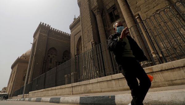 رجل يرتدي قناع وجه يمر بجوار مسجد الرفاعي حيث لم يحضر المسلمون صلاة الجمعة بسبب انتشار مرض كورونا - سبوتنيك عربي