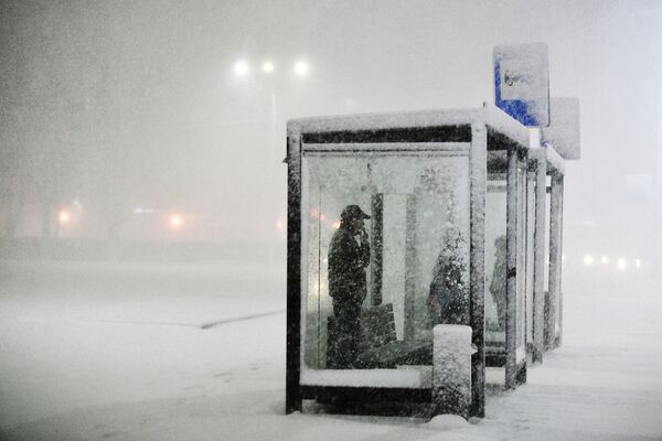 أشخاص يقفون في محطة النقل العام أثناء تساقط الثلوج في بودولسك الروسية، 14 ملرس 2020 - سبوتنيك عربي