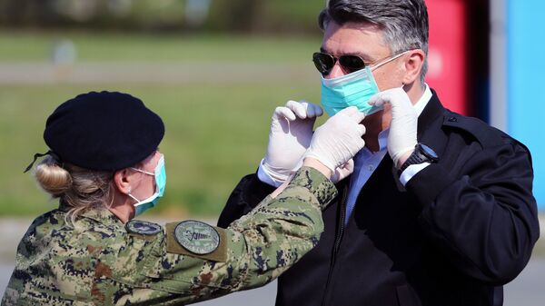 جندي يساعد الرئيس الكرواتي زوران ميلانوفيتش على ارتداء قناع للوجه قبيل زيارته الخيام التي تم إنشاءها لمرضى الفيروس التاجي (COVID-19) في مستشفى دوبرافا في زغرب، كرواتيا 21 مارس 2020. - سبوتنيك عربي