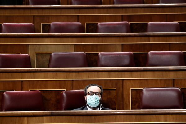 خوسيه ماريا ساننشيز غارسيا، نائب حزب اليمين المتطرف الإسباني  يرتدي القناع الواقي، يجلس في البرلمان الإسباني شبه الخالي، بينما يتبع غالبية المشرعين الجلسة عبر الإنترنت، وهو يشرح  سانشيز الإجراءات الاحترازية اللازمة في ظل حالة الطوارئ في مدريد، إسبانيا 18 مارس 2020 - سبوتنيك عربي