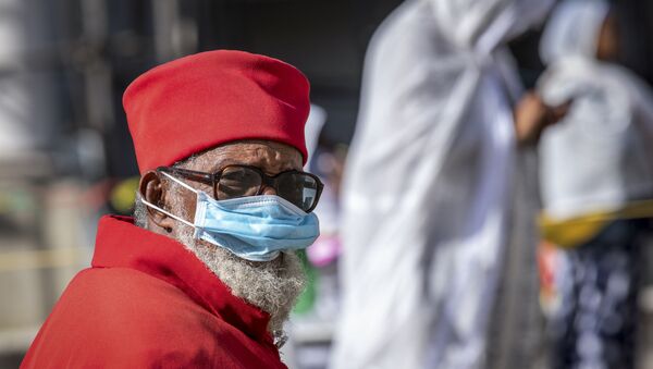 كاهن يرتدي قناعًا للحد من خطر الإصابة بفيروس كورونا الجديد وهو يحضر قداسًا صباح الأحد في كاتدرائية بولي مدهان عالم الإثيوبية الأرثوذكسية في أديس أبابا  - سبوتنيك عربي