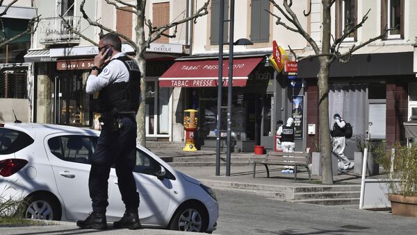 ضابط شرطة يجري مكالمة هاتفية بعد أن هاجم رجل يحمل سكينًا السكان الذين يغامرون بالتسوق في بلدة رومان سور إيزير تحت الإغلاق جنوب فرنسا - سبوتنيك عربي