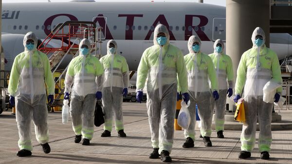 موظفو شركة قطر لخدمات الطيران يرتدون ملابس واقية كإجراء سلامة أثناء فيروس كورونا - سبوتنيك عربي