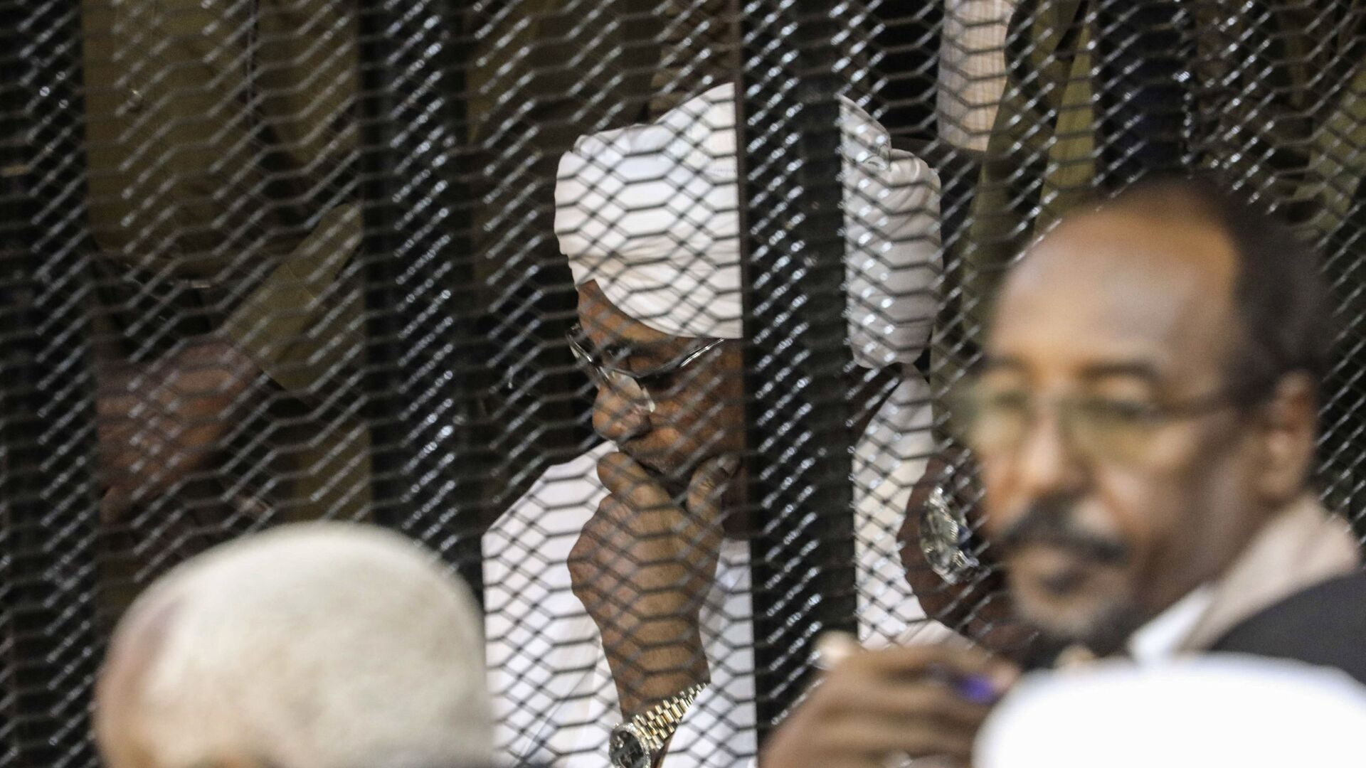 الرئيس السوداني السابق عمر البشير في قفص أثناء محاكمته بتهم الفساد وغسيل الأموال في الخرطوم - سبوتنيك عربي, 1920, 17.07.2021