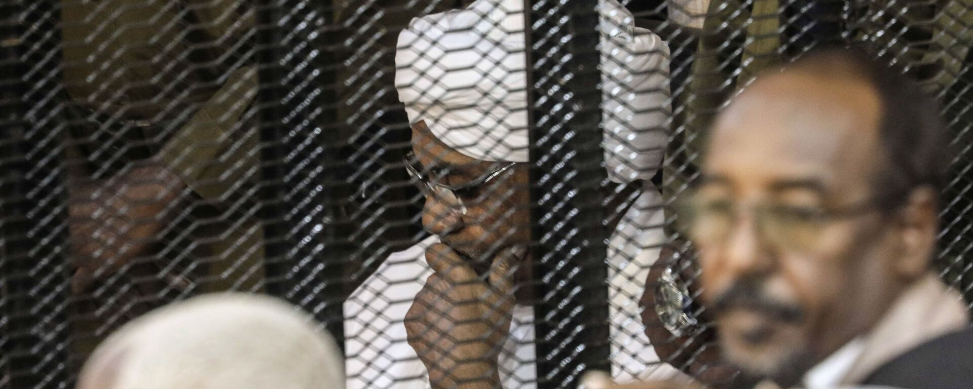 الرئيس السوداني السابق عمر البشير في قفص أثناء محاكمته بتهم الفساد وغسيل الأموال في الخرطوم - سبوتنيك عربي, 1920, 02.06.2021