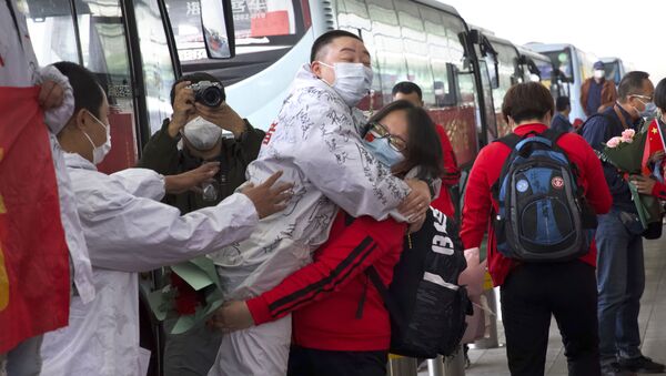 عاملة طبية من مقاطعة جيلين الصينية تحتضن زميل من ووهان وهي تستعد للعودة إلى المنزل في مطار ووهان - سبوتنيك عربي