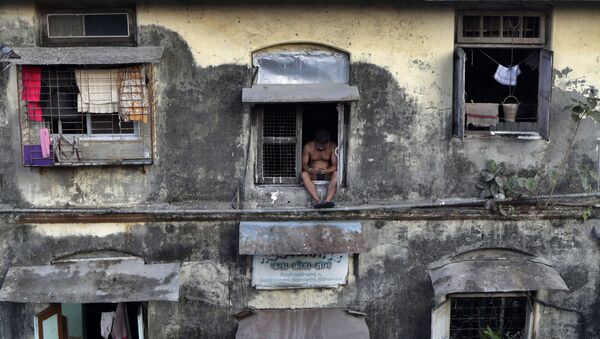 رجل يجلس على نافذة في شقته، أثناء الإغلاق التام لمنع انتشار الفيروس التاجي كورونا الجديد، في منطقة بارل في مومباي، الهند 5 أبريل 2020 - سبوتنيك عربي