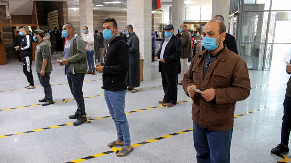 مواطنون يرتدون كمامات طبية كجزء من اجراءات وقائية مرض فيروس كورونا (كوفيد-19)، وهم يقفون على بعد مسافة آمنة وفق معايير منظمة الصحة العالمية، في طوابير في أحد البنوك في مصراتة، ليبيا  22 مارس / آذار 2020 - سبوتنيك عربي