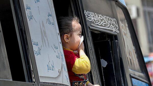 فتاة تحمي فمها وسط مخاوف من فيروس كورونا وتطل من نافذة حافلة في القاهرة - سبوتنيك عربي