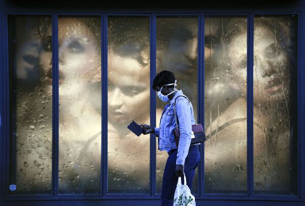 امرأة ترتدي كمامة طبية تمر بجوار نافذة متجر في باريس في 14 أبريل 2020، في اليوم التاسع والعشرين من الحجر الصحي المعلن في فرنسا، في إطار الاجراءات الوقائية لمنع انتشار فيروس كورونا (اوفيد-19). - سبوتنيك عربي