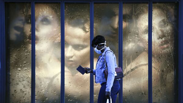 امرأة ترتدي كمامة طبية تمر بجوار نافذة متجر في باريس في 14 أبريل 2020، في اليوم التاسع والعشرين من الحجر الصحي المعلن في فرنسا، في إطار الاجراءات الوقائية لمنع انتشار فيروس كورونا (اوفيد-19). - سبوتنيك عربي