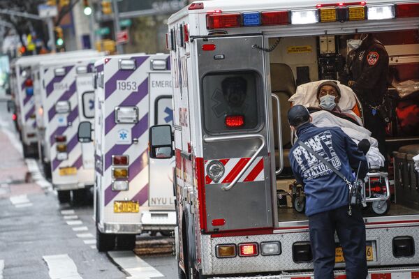 مريض يصل بسيارة إسعاف برعاية عاملين طبيين يرتدون معدات وقائية بسبب مخاوف كوفيد-19  خارج مركز جامعة نيويورك لانغون الطبي، 13 أبريل 2020 ، في نيويورك، الولايات المتحدة - سبوتنيك عربي