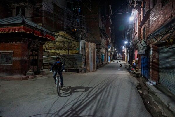 رجل يرتدي  كمامة طبية ويركب دراجة على أحد الشوارع في ضواحي كاتماندو. وقرر مجلس وزراء نيبال تمديد الحجر الصحي كتدبير وقائي لمنع انتشار فيروس كورونا المسبب لمرض كوفيد-19 حتى 27 أبريل. - سبوتنيك عربي