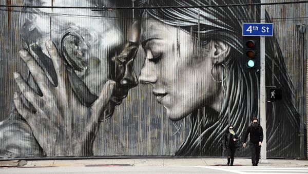 أشخاص يرتدون الكمامات وهم يعبرون الشارع أمام جدارية في حي الفنون في لوس أنجلوس، حيث تستمر أوامر البقاء في المنزل في كاليفورنيا بسبب الفيروس التاجي كورونا، 10 أبريل 2020. - سبوتنيك عربي
