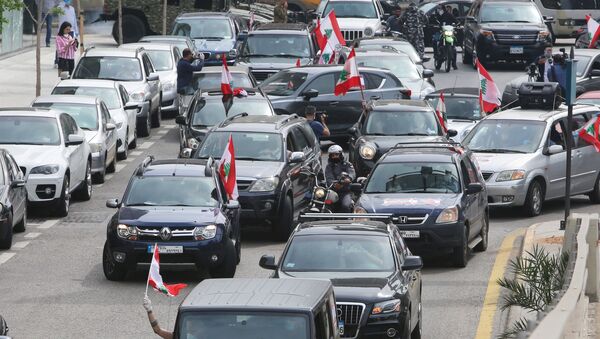 متظاهرون مناهضون للحكومة يحملون أعلاماً لبنانية وهم يحتجون في سياراتهم خلال إغلاق البلاد لمكافحة انتشار فيروس كورونا (COVID-19) في بيروت - سبوتنيك عربي