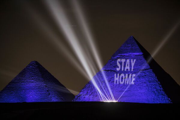إضاءة أهرامات الجيزة عبارة ابق في البيت في القاهرة، في إطار حملة توعوية لمنع انتشار فيروس كورونا في مصر، 18 أبريل 2020 - سبوتنيك عربي